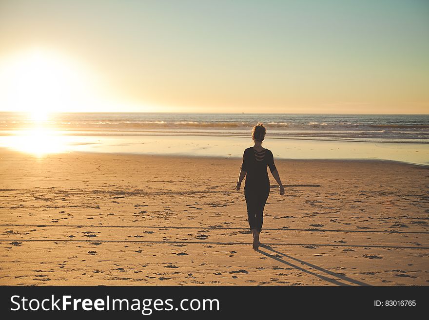 A girl on the beach with sun low in the horizon. A girl on the beach with sun low in the horizon.