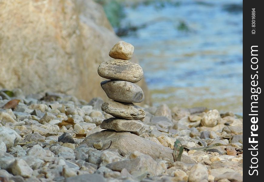 Closeup of an unstable pile of stones on a river bank or beside the sea with selective focus, blurred blue background. Closeup of an unstable pile of stones on a river bank or beside the sea with selective focus, blurred blue background.