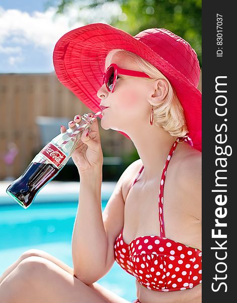 Woman In Red Polka Dot Print Bikini Wearing Red Frame Sunglasses Drinking Coca Cola Beverage In Blue And White Clouds