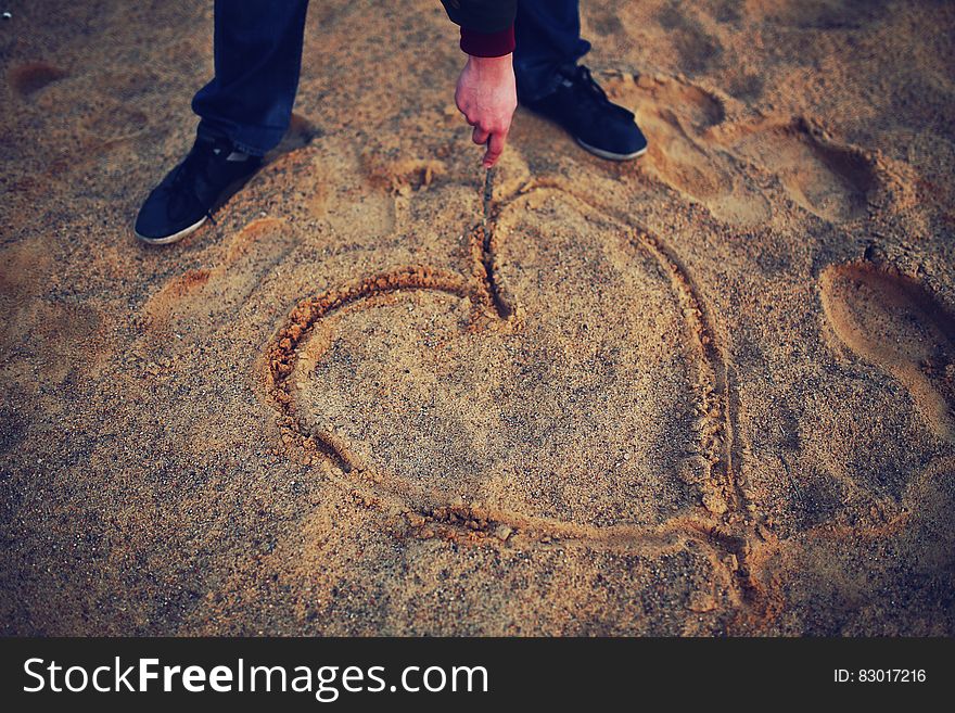 Hand drawing heart in the sand