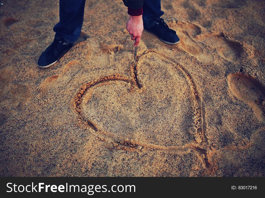 Hand Drawing Heart In The Sand