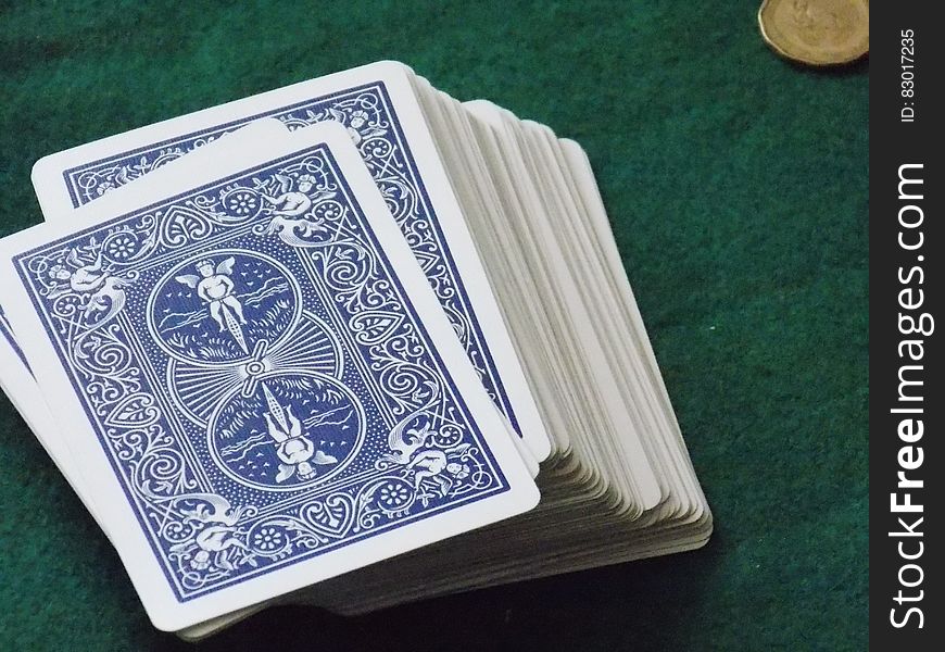A deck of cards and a coin on green background.