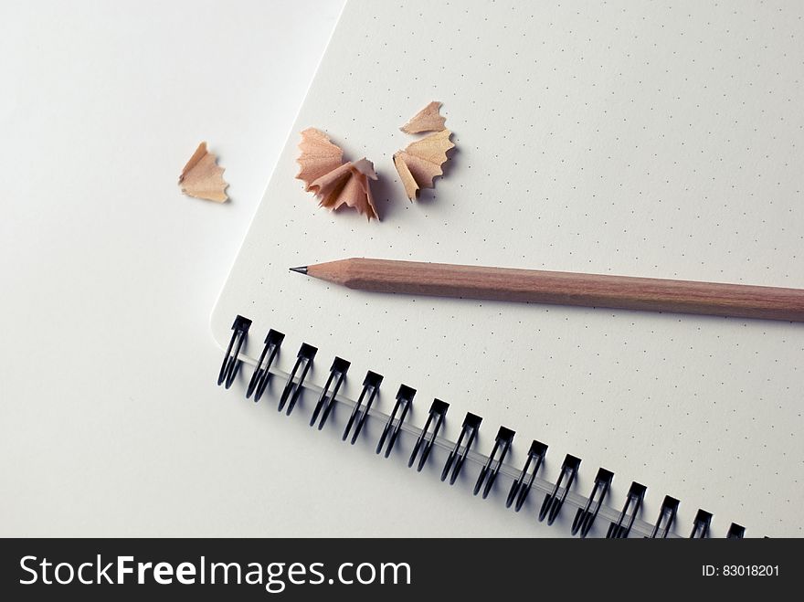 Wooden pencil with shavings on blank page of notebook. Wooden pencil with shavings on blank page of notebook.