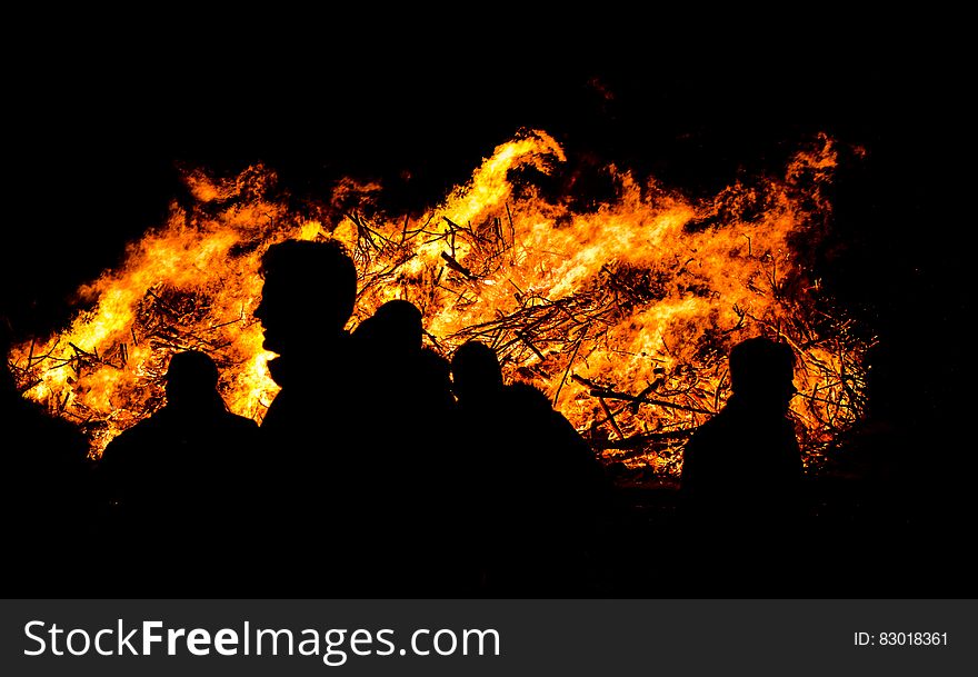 Silhouette of people outdoors next to bonfire flames. Silhouette of people outdoors next to bonfire flames.