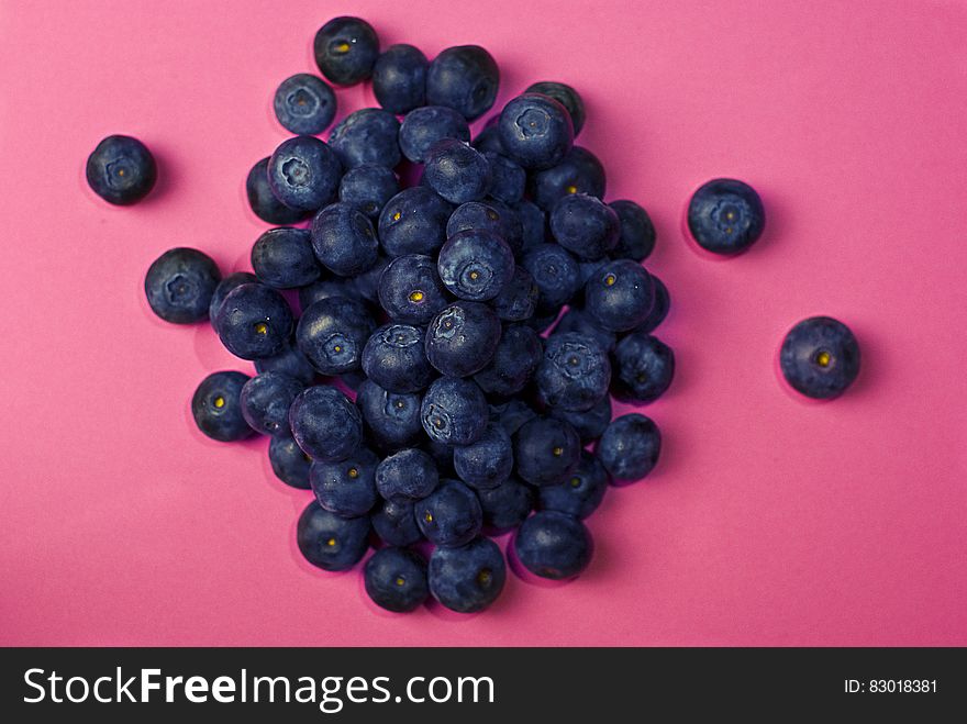Pile of fresh whole blueberries on pink.