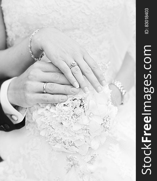 Close up on rings on hands of bride and groom in black and white.