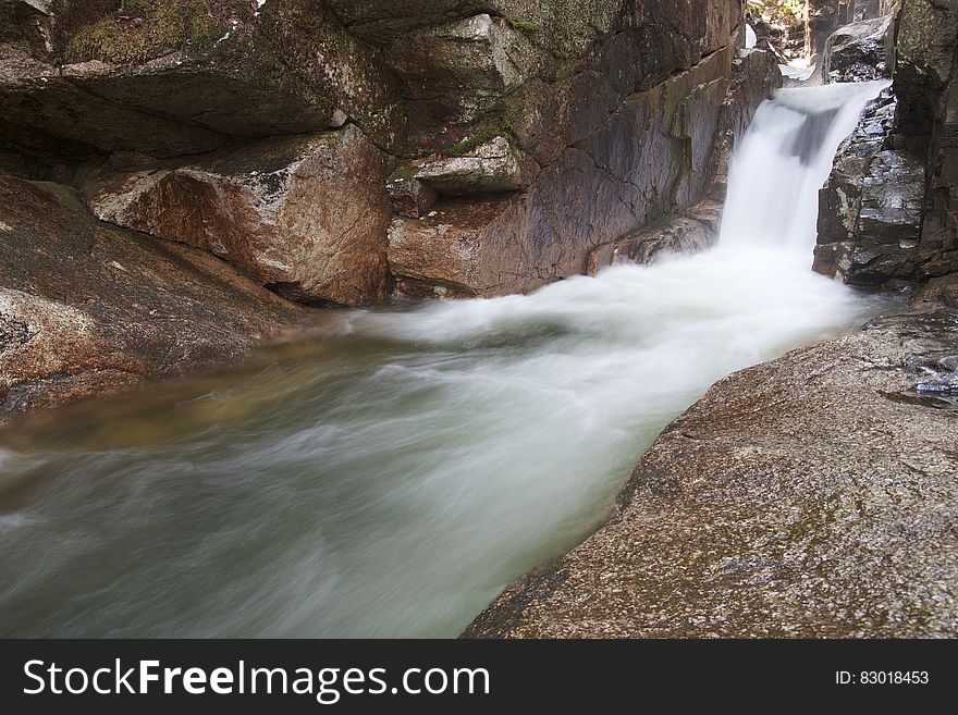 Blur of water over falls along rocky shores in stream. Blur of water over falls along rocky shores in stream.