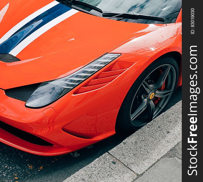 Front of orange Ferrari sports car against curb.