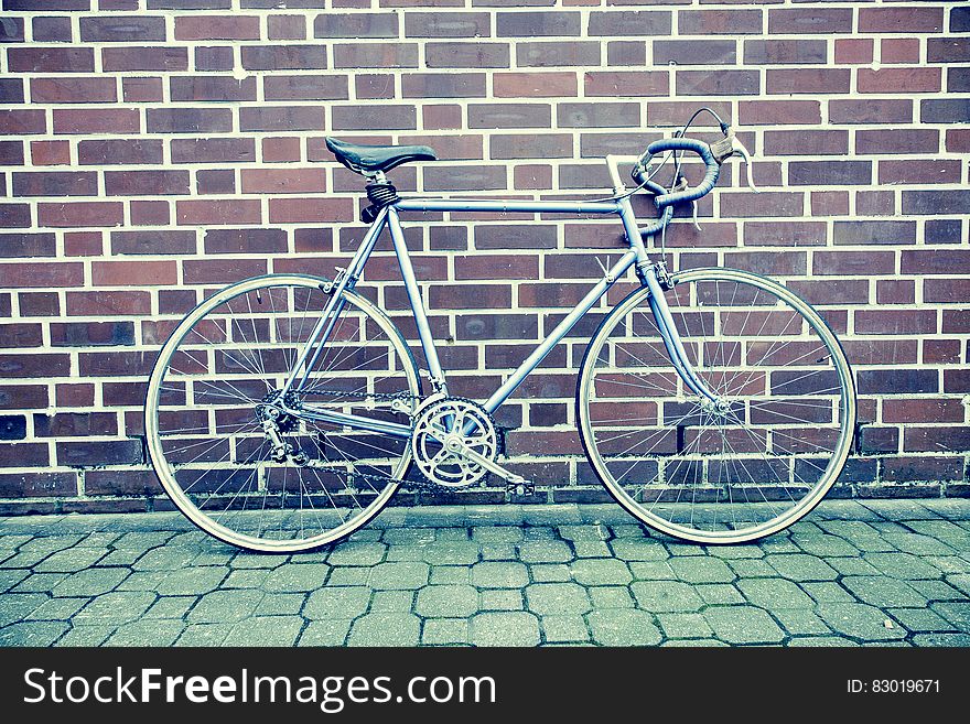 Teal and Black Road Bike Near Black and Brown Brick Wall