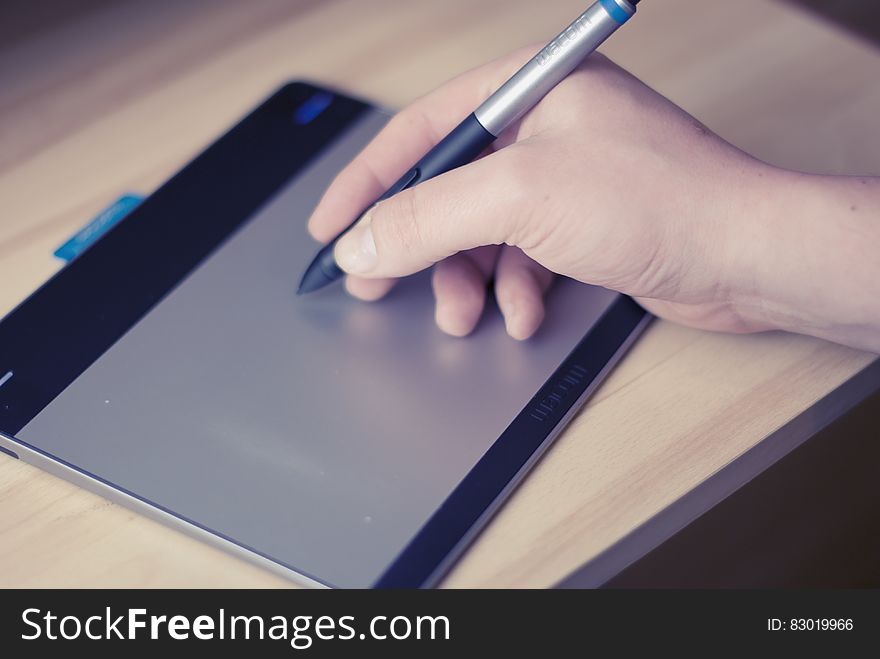 Hand holding stylus writing on tablet screen on desktop. Hand holding stylus writing on tablet screen on desktop.