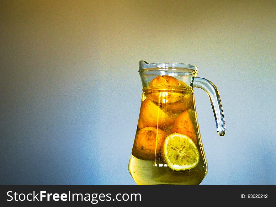 Clear Glass Pitcher With Sliced Yellow Round Fruit Inside