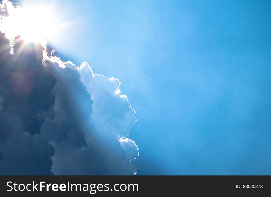 The blue skies with a sun peeking from behind a cloud. The blue skies with a sun peeking from behind a cloud.