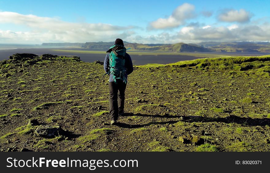 Person In Green Coat Walking On Mountain