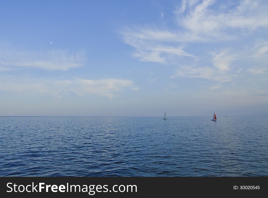 Small yachts sailing on calm blue sea with cloudscape background. Small yachts sailing on calm blue sea with cloudscape background.