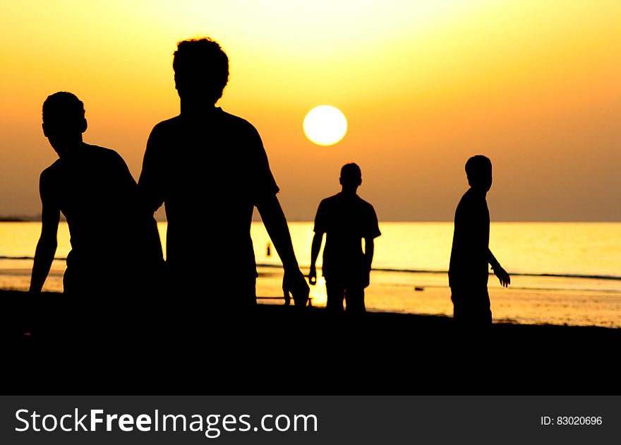 Silhouette Of 4 People Near Ocean During Sunset