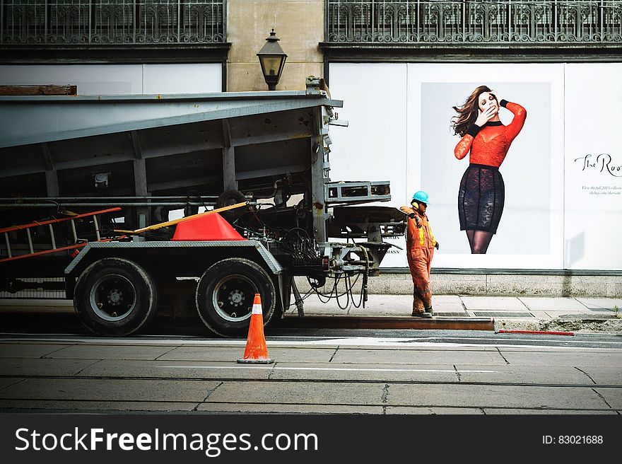 Man in Orange Safety Suit Standing Beside Truck Bed