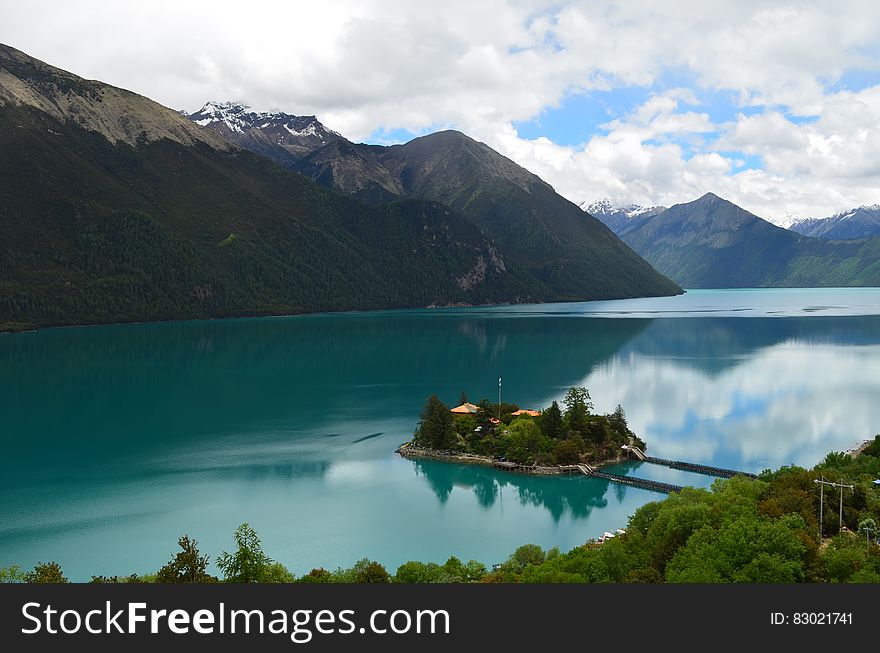 Green Small Island Sorrounded By Bodies Of Water Under Cloudy Sky