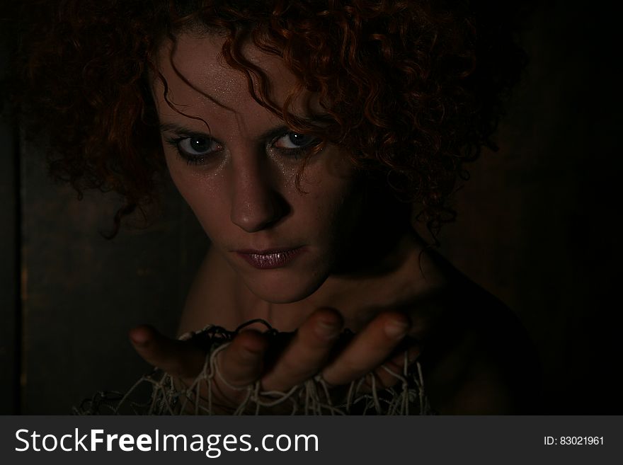 Portrait of woman in shadows holding netting in open palms.