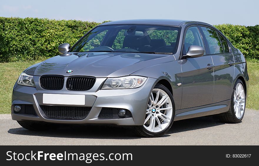 Luxury car, a German made BMW Series 3 saloon in silver with alloy wheels, green garden background. Luxury car, a German made BMW Series 3 saloon in silver with alloy wheels, green garden background.