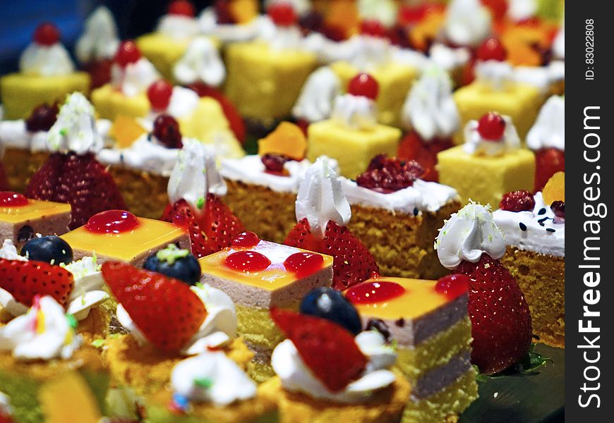 A bunch of small cakes with fruits and cream for serving. A bunch of small cakes with fruits and cream for serving.