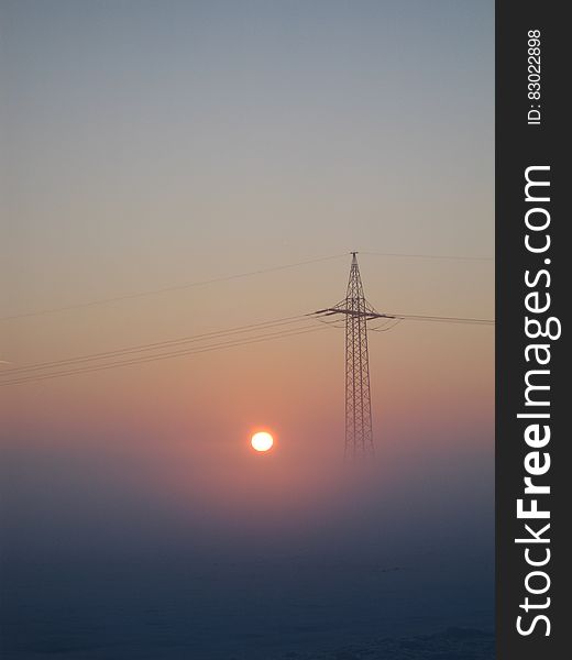 Electricity Pylon In Foggy Sunrise