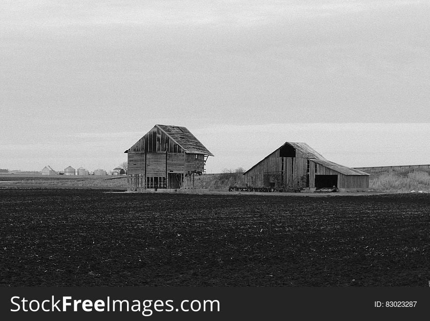 Wooden barns in plowed farm fields in black and white. Wooden barns in plowed farm fields in black and white.