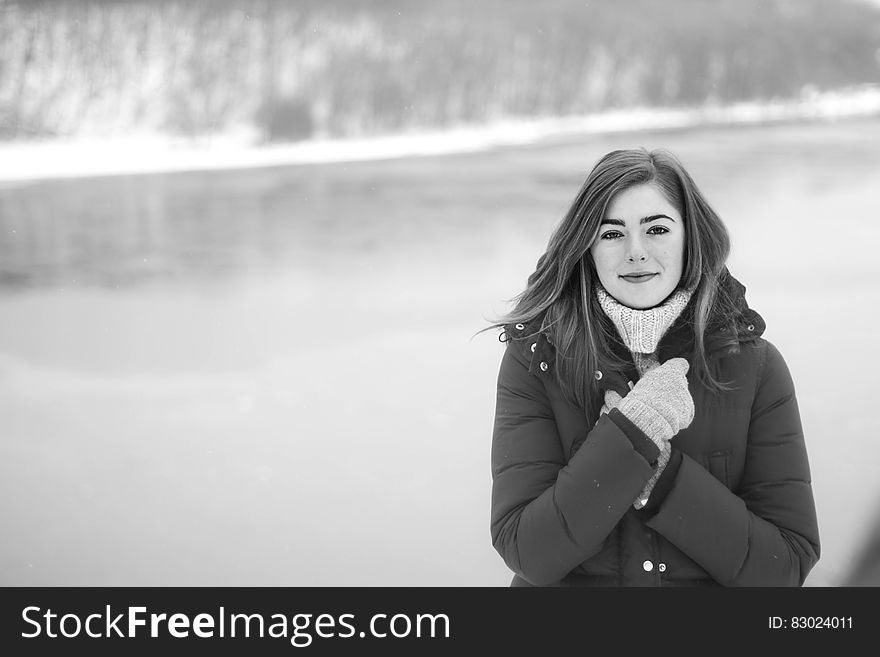 Brown Haired Woman In Black Puffer Coat Standing Near The Water