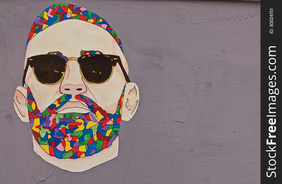 Graffiti art of man with colorful hair and beard wearing sunglasses on wall. Graffiti art of man with colorful hair and beard wearing sunglasses on wall.