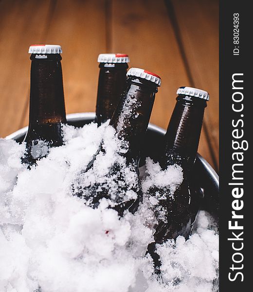 Close up of brown beverage bottles covered in chipped ice in metal tub. Close up of brown beverage bottles covered in chipped ice in metal tub.