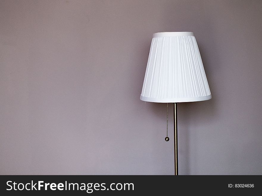 White and Grey Metal Pedestal Lamp Nearby Grey Painted Wall