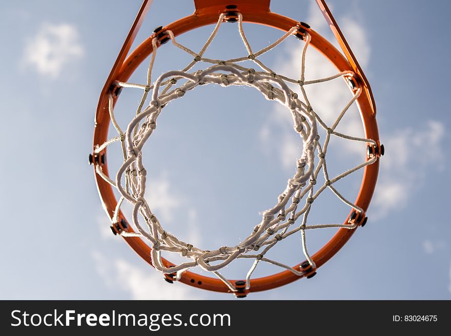 A close up shot of a red basketball basket and blue sky in the background.