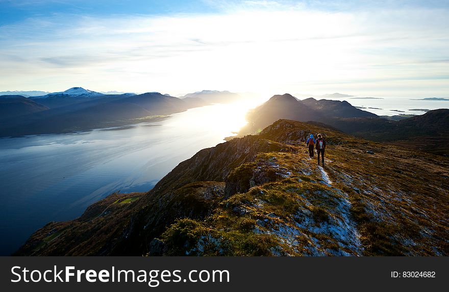 Hikers on the mountain top above a lake at sunrise. Hikers on the mountain top above a lake at sunrise.