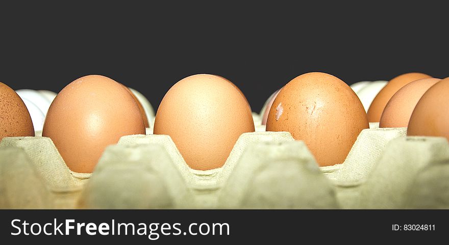 A close up shot of eggs in an egg carton on a black background.