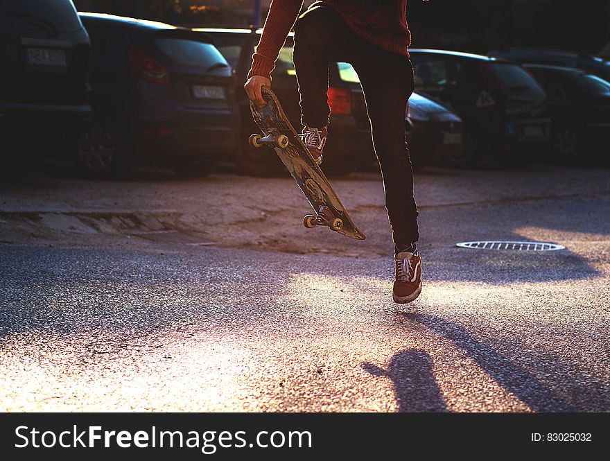 Person in Red Long Sleeved Shirt and Black Skinny Pants Riding a Skateboard