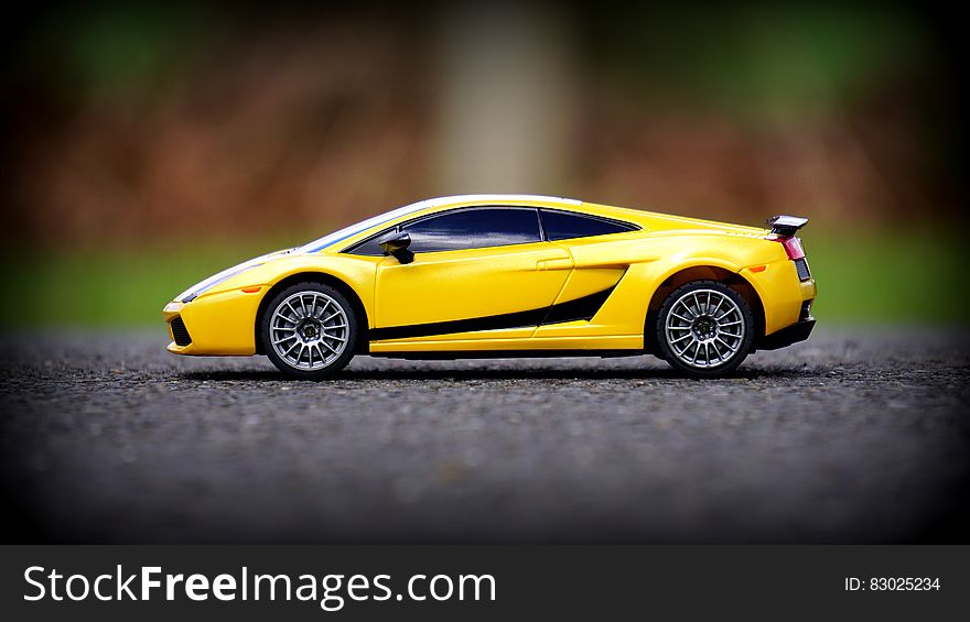 A yellow toy Lamborghini car on asphalt.