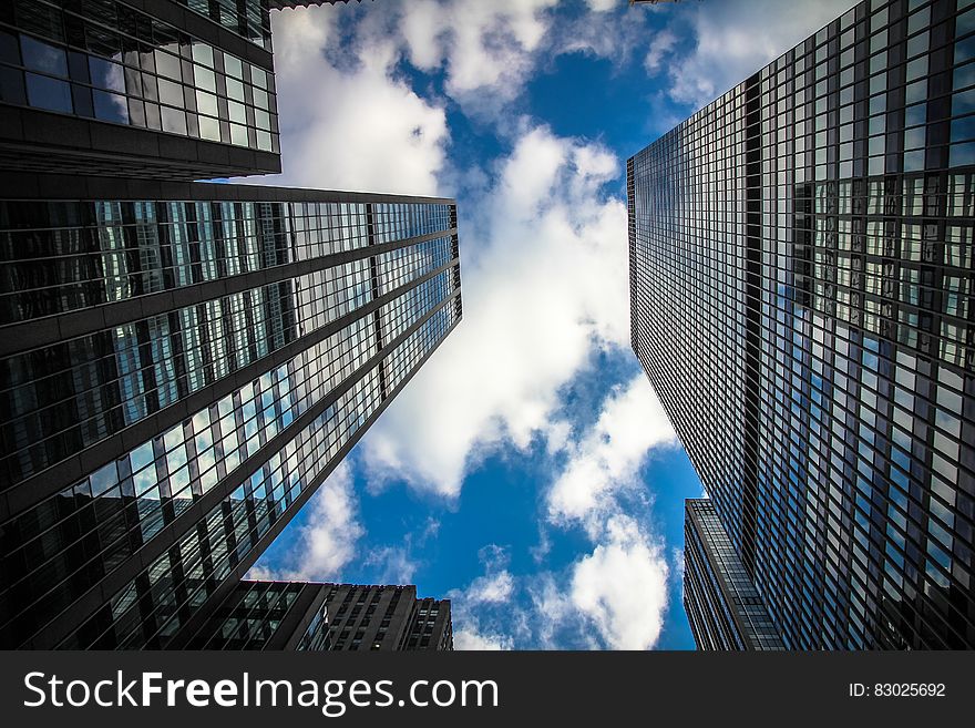 Facade of mirrored modern skyscrapers against blue skies with clouds. Facade of mirrored modern skyscrapers against blue skies with clouds.