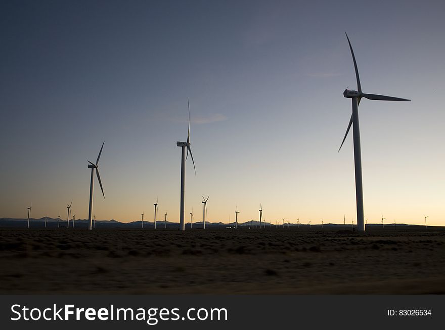 Silhouette of wind turbines in rural field at sunset. Silhouette of wind turbines in rural field at sunset.