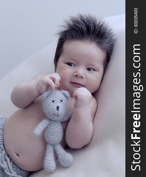 Portrait of Asian baby with crochet doll on white pillow. Portrait of Asian baby with crochet doll on white pillow.