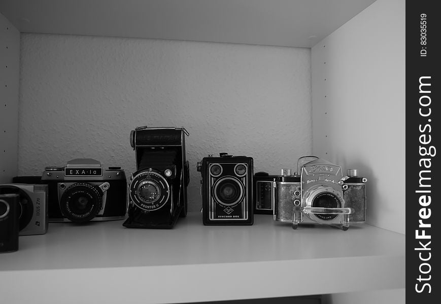 Close up of vintage camera equipment on shelf in black and white.