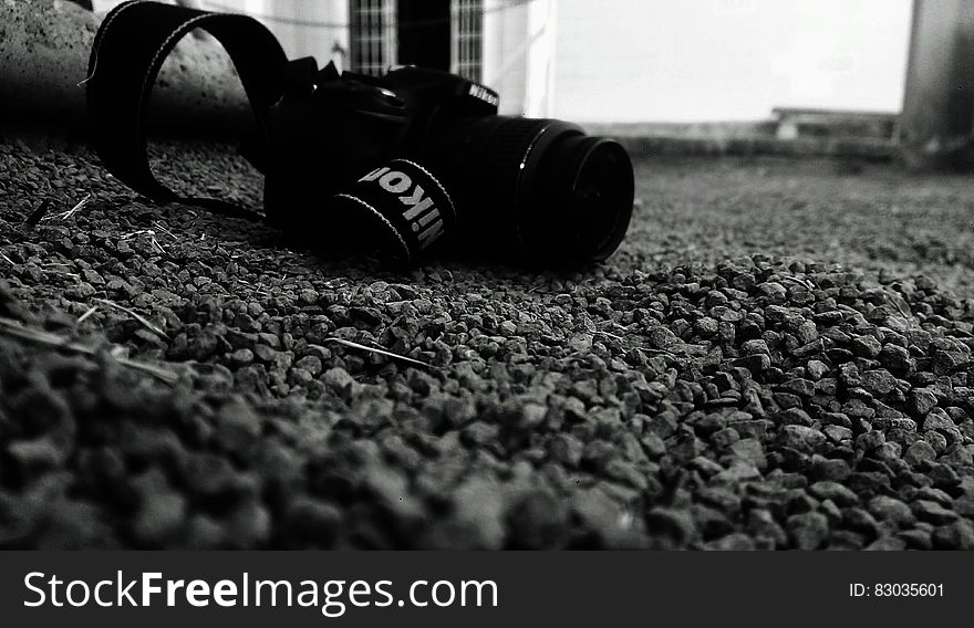 Nikon camera on pebbles on ground in black and white.