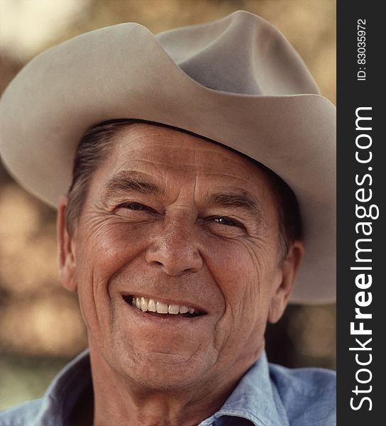 A portrait of president Ronald Reagan smiling with a hat on his head. A portrait of president Ronald Reagan smiling with a hat on his head.