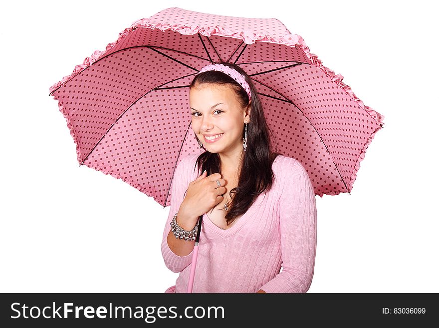 A smiling young woman under a pink polka dot umbrella. A smiling young woman under a pink polka dot umbrella.