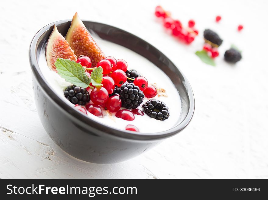 China bowl of cream with fresh fruit berries on white counter top. China bowl of cream with fresh fruit berries on white counter top.