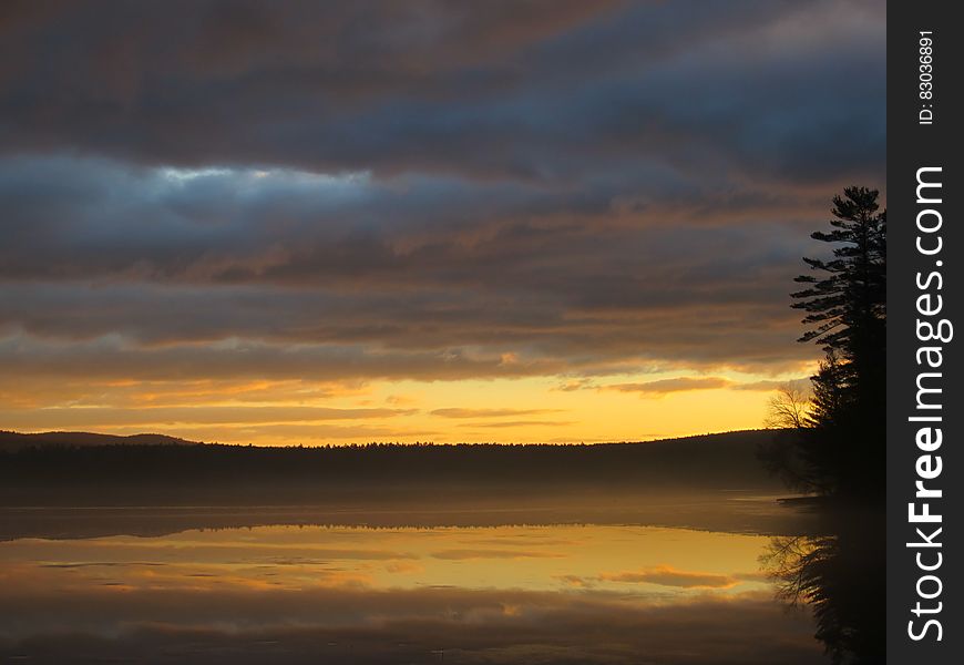 A sunrise is reflected over a lake. A sunrise is reflected over a lake.