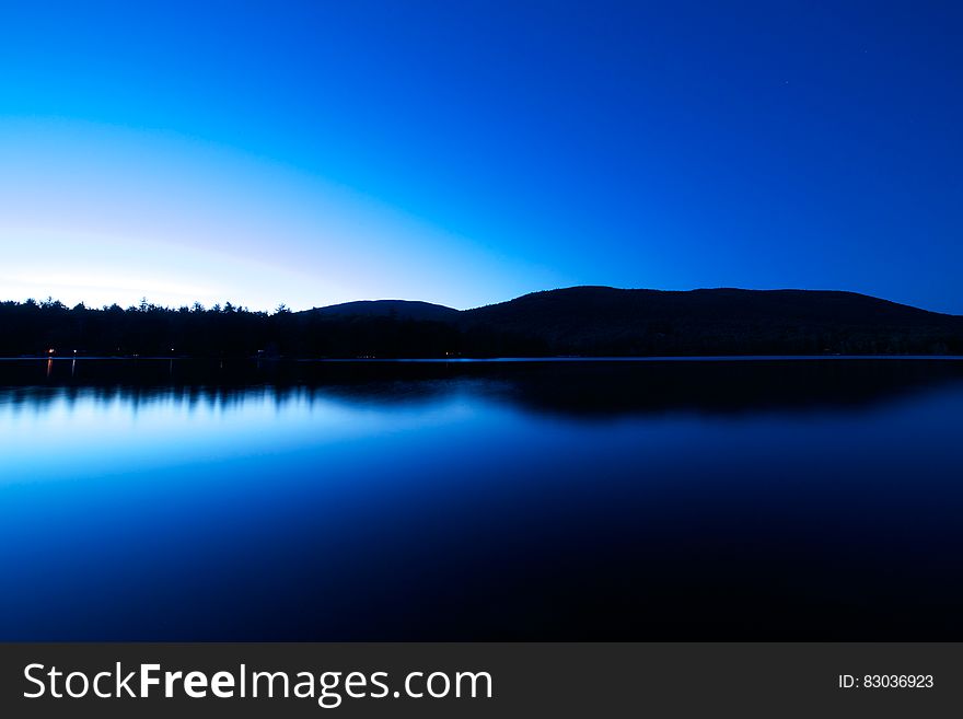 A blue lake with a dark blue sky at night.