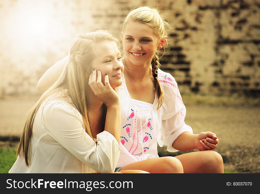 Two Women Sitting Down Smiling