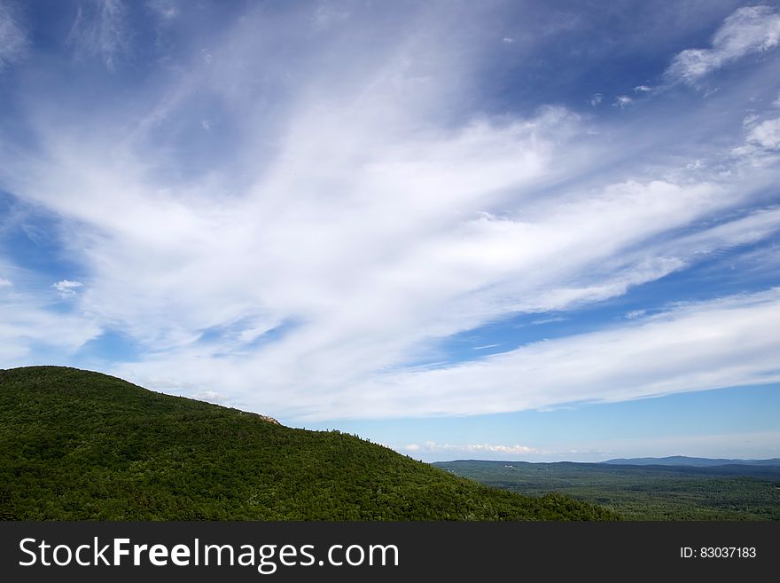 White clouds over green hills.