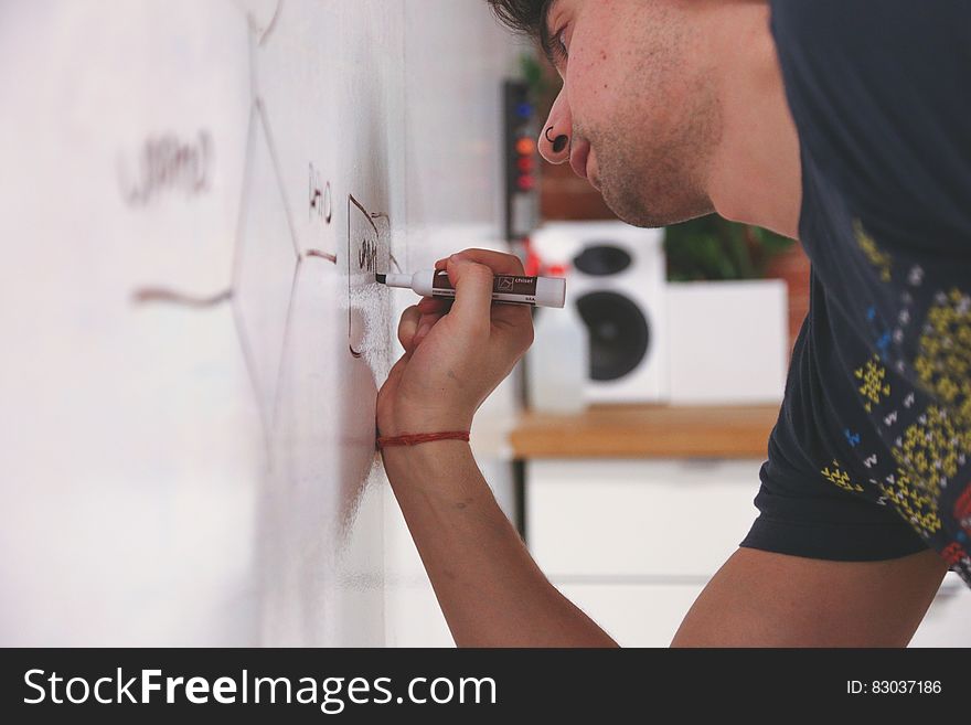 Young man leaning over and drawing on whiteboard with marker pen. Young man leaning over and drawing on whiteboard with marker pen.