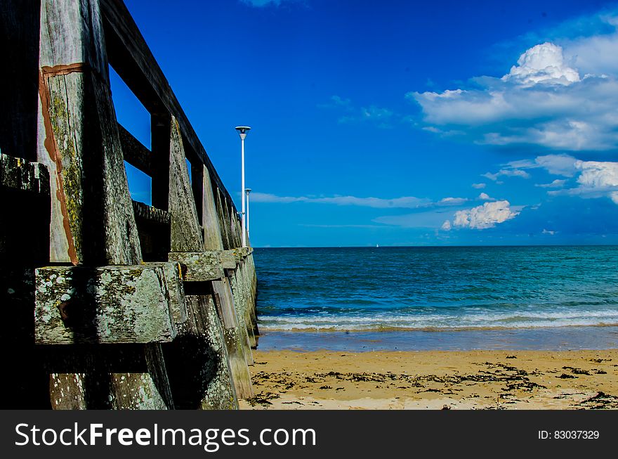 Brown Wooden Bar Near Sea Shore Under Blue Sky during Day Time