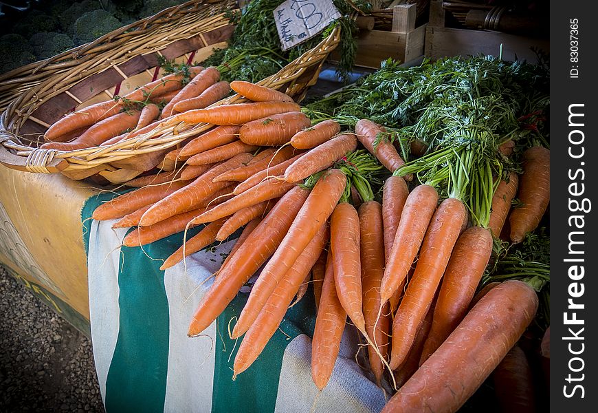 Bunches of fresh organic carrots on a market stall, some in a wicker basket. Bunches of fresh organic carrots on a market stall, some in a wicker basket.